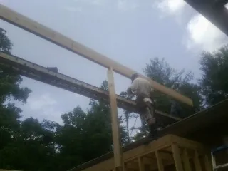 Carpenter setting a ridge beam over a new addition frame — Ice Dam Removal by Roofing Brothers in Crestview
