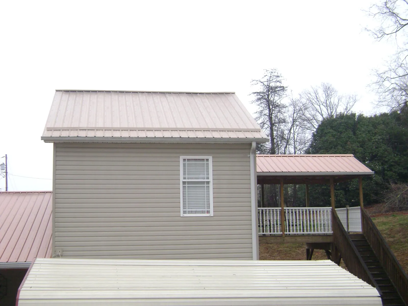 Tan metal roofs on a two story addition and attached porch, from a Roof Replacement job in Crestview