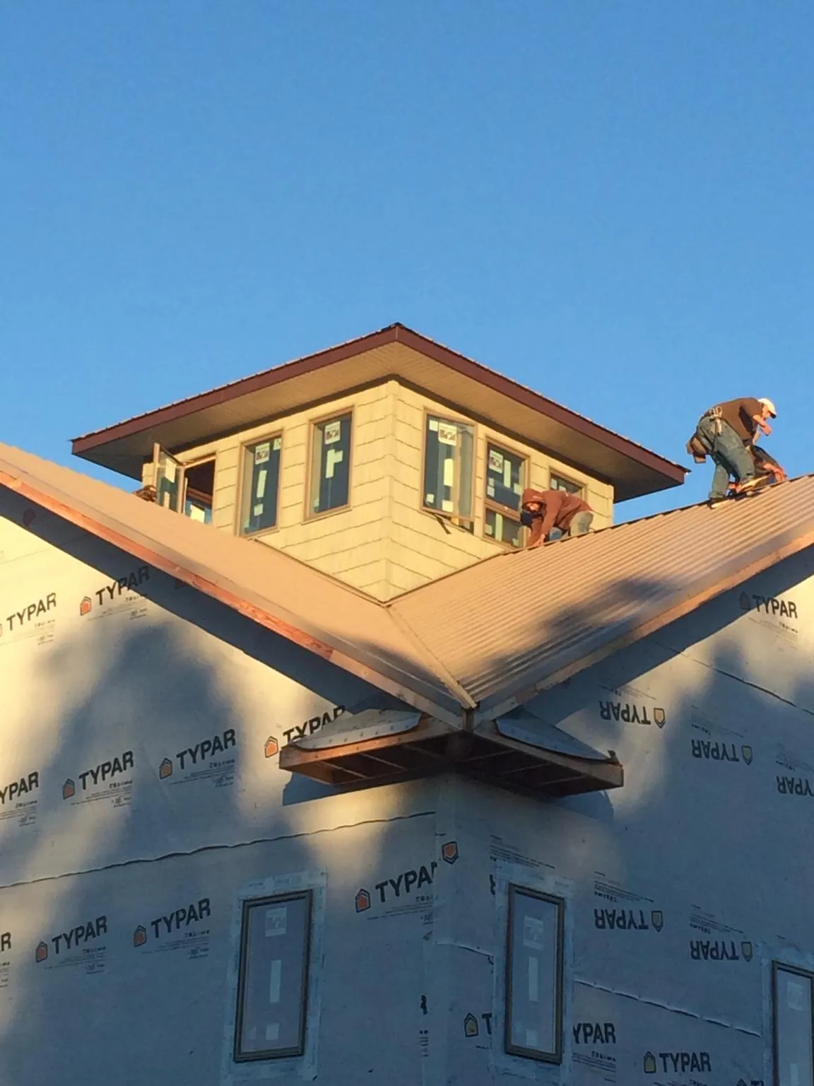 Roofers working around a rooftop cupola on a new metal roof at sunset — Roof Waterproofing in Crestview by Roofing Brothers